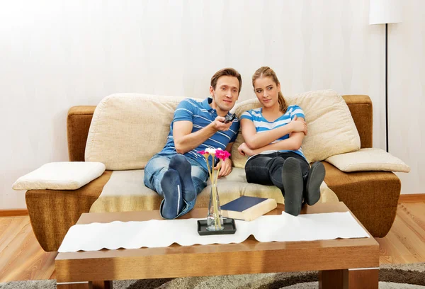 Jovem casal sentado no sofá e assistindo TV — Fotografia de Stock