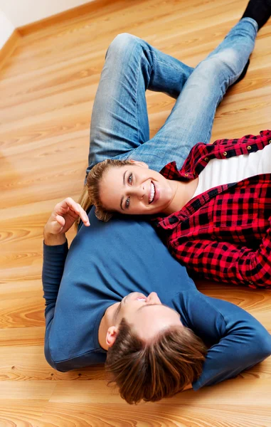 Jovem casal feliz deitado no chão — Fotografia de Stock