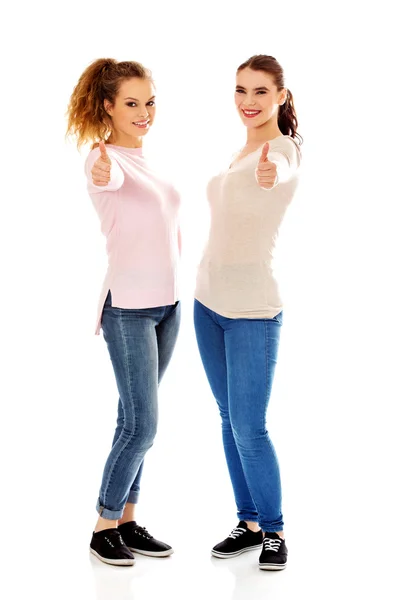 Две молодые счастливые женщины показывают большие пальцы вверх — стоковое фото