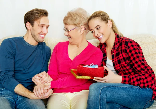 Glückliche Familie - Paar mit alter Frau, die Geschenkbox und Babyschuh in der Hand hält — Stockfoto