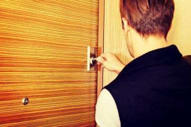 Genç adam eve dönüyor ya da evden çıkıyor.