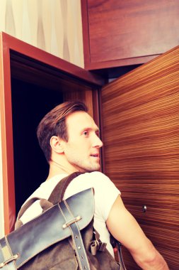 Genç adam eve dönüyor ya da evden çıkıyor.