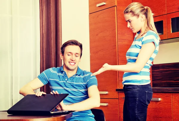 Homem assistindo algo no laptop, sua esposa está com raiva — Fotografia de Stock