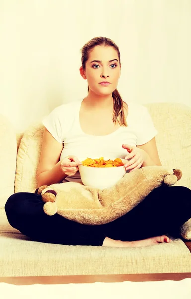 Jeune femme regarder la télévision et manger des chips — Photo