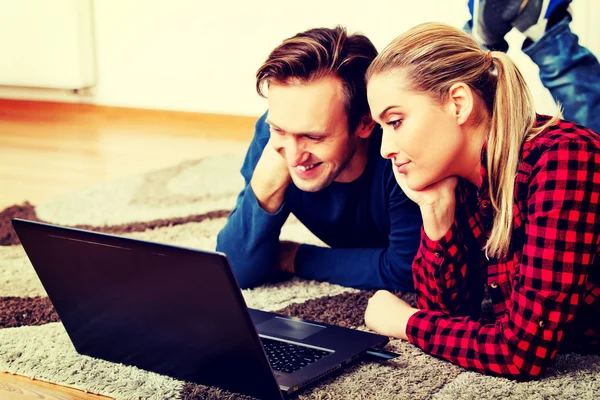 Gelukkig paar liggend op de vloer met laptop — Stockfoto