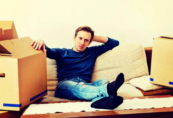 Tired man sitting on couch with cardboard boxes around — Stock Photo, Image