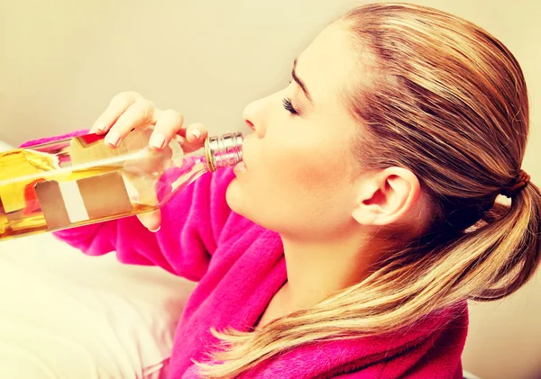 Jeune femme inquiète buvant de l'alcool au lit — Photo