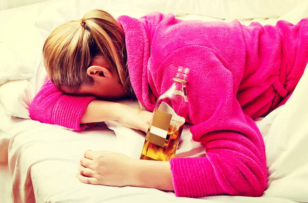 Junge besorgte Frau trinkt Alkohol im Bett — Stockfoto