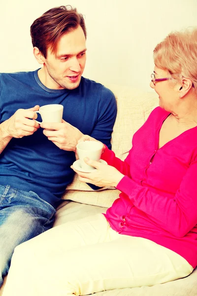 Mor och son sitter på soffan och dricka te eller kaffe — Stockfoto