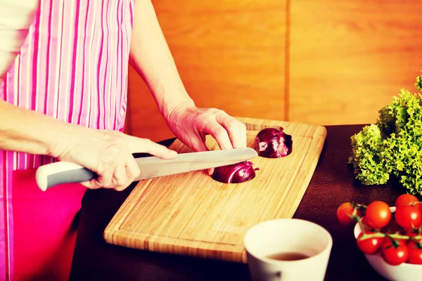 Frau schnitt rote Zwiebel auf Schneidebrett — Stockfoto
