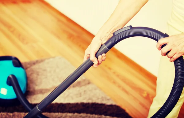 Senior woman vacuuming carpet at home — Stock Photo, Image