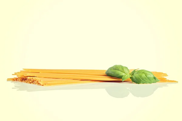 Uncooked dry fettuccine pasta  with green basil — Stock Photo, Image