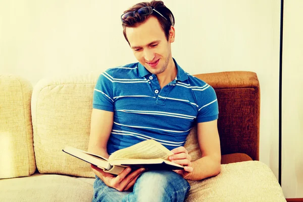 Człowiek siedzi na kanapie i czytanie książki — Zdjęcie stockowe