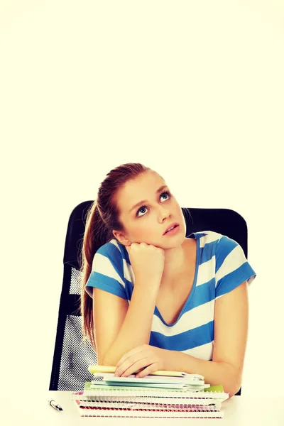 Teenage woman sitting behind the desk and thinking — Stock Photo, Image