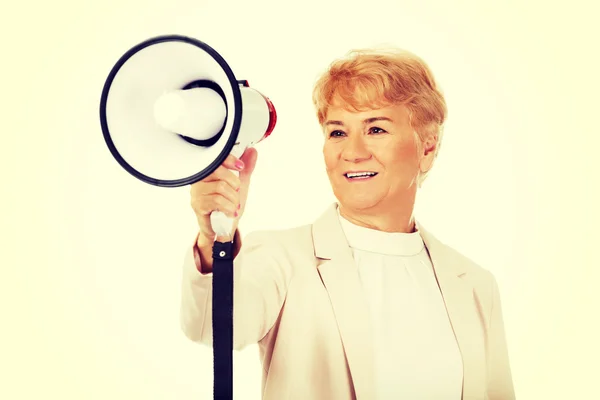 Senior donna sorridente urlando attraverso un megafono — Foto Stock