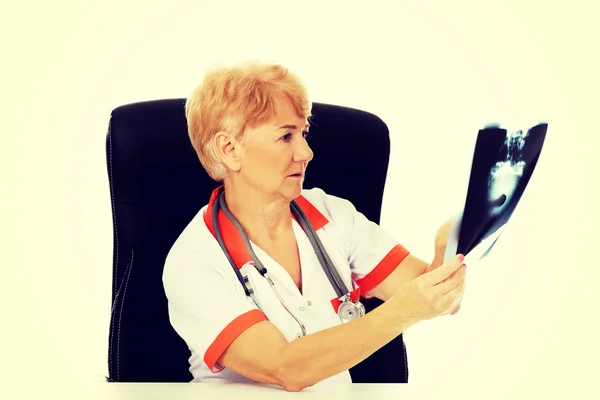 Médica idosa pensiva à procura de foto de raios-x — Fotografia de Stock