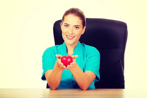 Young female doctor holding toy heart — Stock Photo, Image