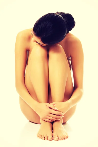 Mujer desnuda sentada con la cabeza sobre las rodillas —  Fotos de Stock