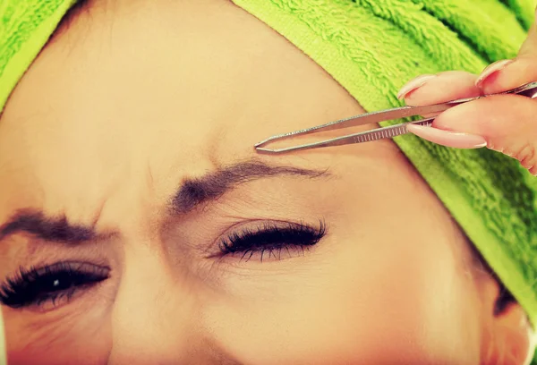 Beautiful woman plucking her eyebrow. — Stock Photo, Image