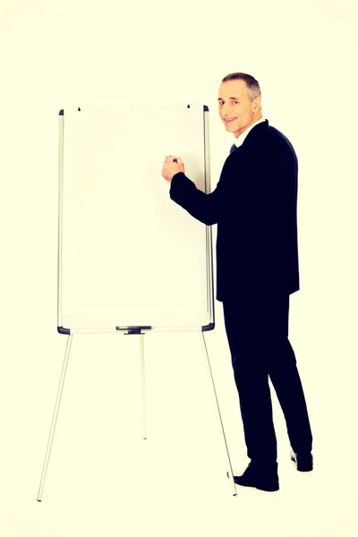 Male executive writing on a flipchart — Stock Photo, Image