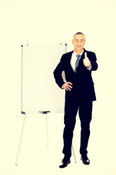 Executivo masculino com ok sinal perto de flip chart — Fotografia de Stock