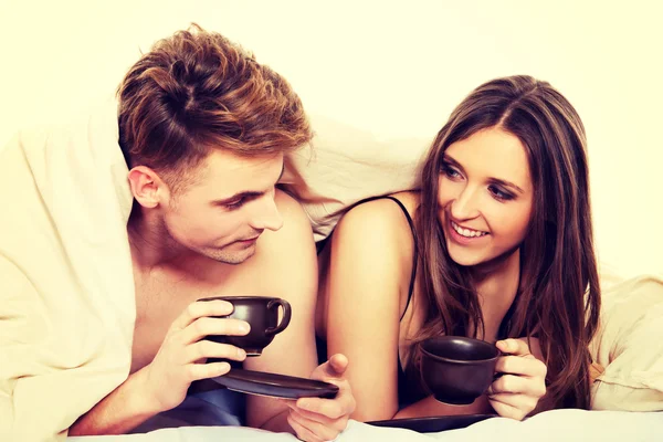 幸福的夫妇在床上喝咖啡. — 图库照片