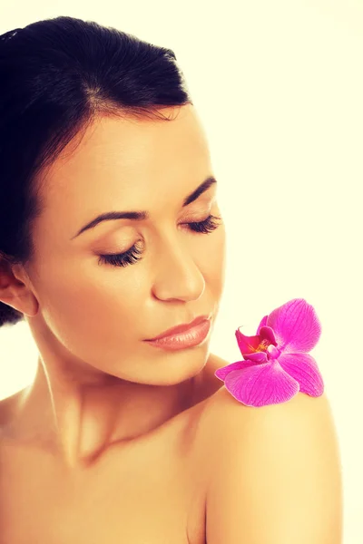 Mulher com pétala de orquídea roxa no ombro — Fotografia de Stock