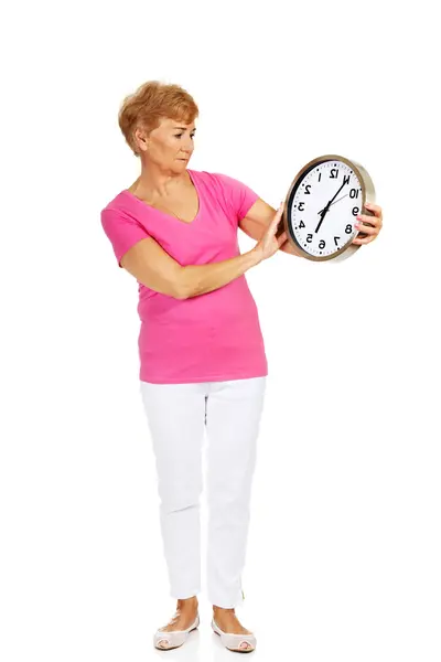 Worried senior woman holding big clock — Stock Photo, Image