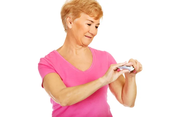 Smiling senior woman holding toothpaste and toothbrush — Stock Photo, Image