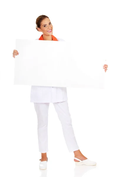 Happy female doctor or nurse holding empty banner — Stock Photo, Image