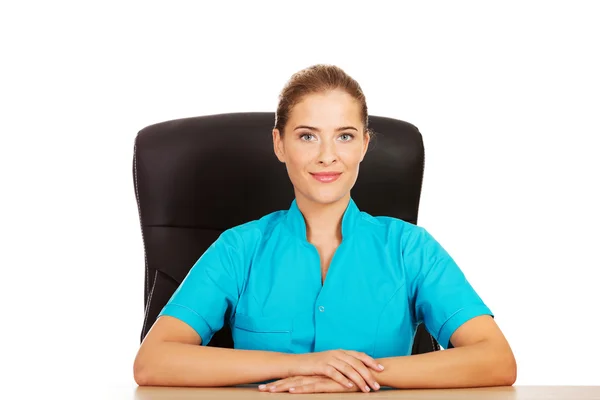 Jovem médica ou enfermeira sentada atrás da mesa — Fotografia de Stock