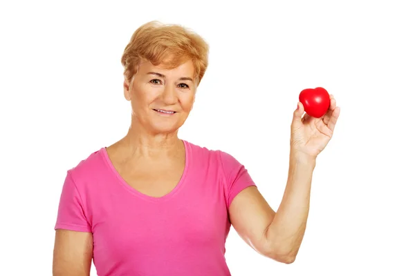 Old smiling woman holding red toy heart Royalty Free Stock Photos