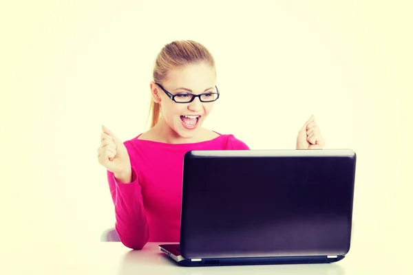Молода щаслива жінка сидить перед ноутбуком . — стокове фото