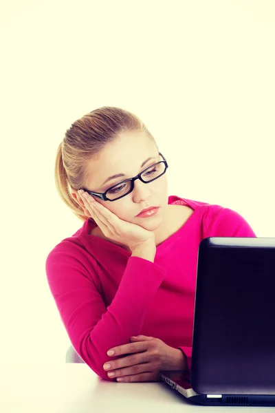 Mujer aburrida y triste sentada frente al portátil . — Foto de Stock