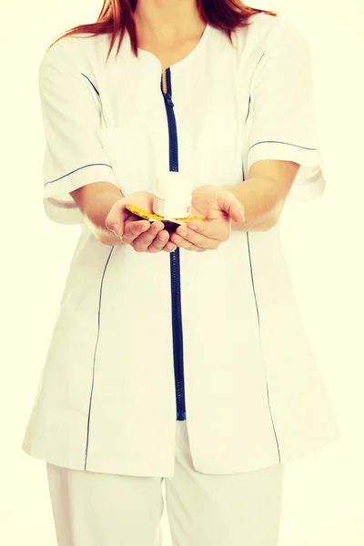 Young female nurse holding pills. — Stock Photo, Image