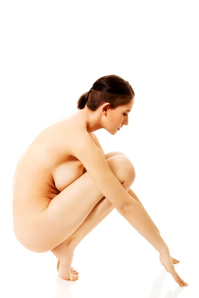 Vista lateral mujer desnuda sentadillas en el suelo —  Fotos de Stock