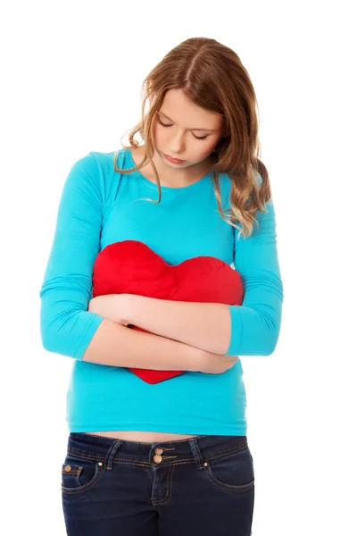 Young woman with heart shaped pillow — Stock Photo, Image