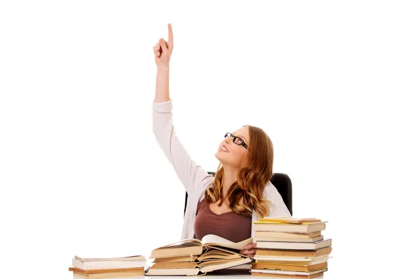 Young woman with books pile pointing up — Stock Photo, Image