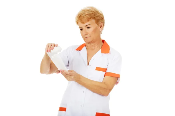 Болезненная пожилая женщина врач или медсестра держит повязку — стоковое фото