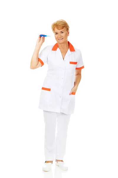 Sorria idosa médica ou enfermeira segurando termômetro — Fotografia de Stock
