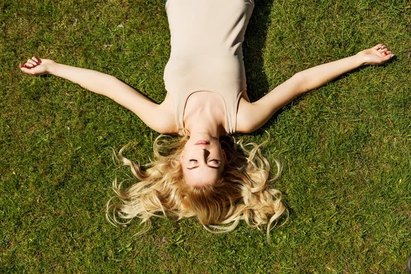 Mujer joven feliz acostada en la hierba — Foto de Stock