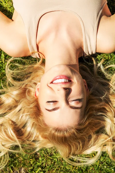 Mujer joven feliz acostada en la hierba — Foto de Stock