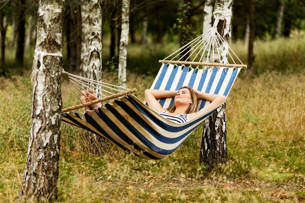 Genç sarışın kadın hamakta dinleniyor.