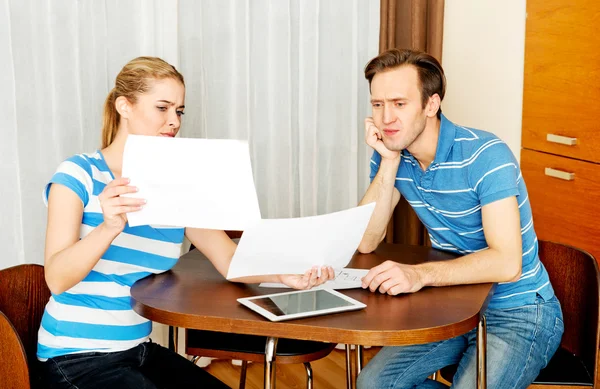 Junges Paar sitzt am Schreibtisch und sucht Pläne für ein neues Haus — Stockfoto