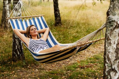 Genç sarışın kadın hamakta dinleniyor.