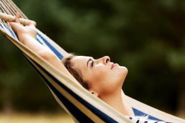 Genç sarışın kadın hamakta dinleniyor.