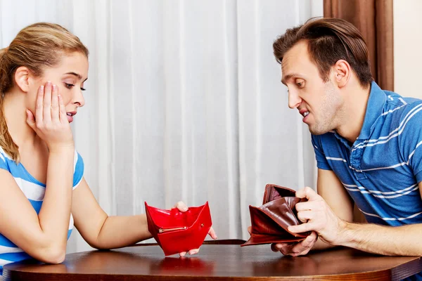 Worried couple sitting at the table with empty wallets — Stock Photo, Image