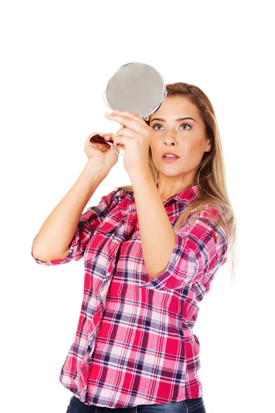 Ung kvinna håller en spegel och kammar sitt hår — Stockfoto