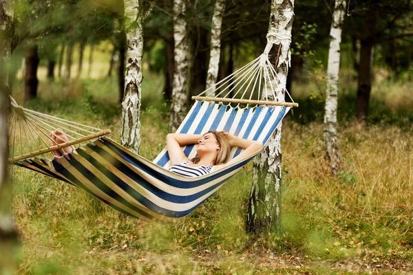 Mladá blondýna žena odpočívající na houpací síti — Stock fotografie