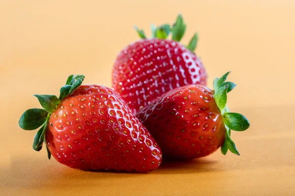 Three juicy strawberry on orange background — Stock Photo, Image